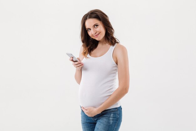 Mulher gravida isolada usando telefone celular