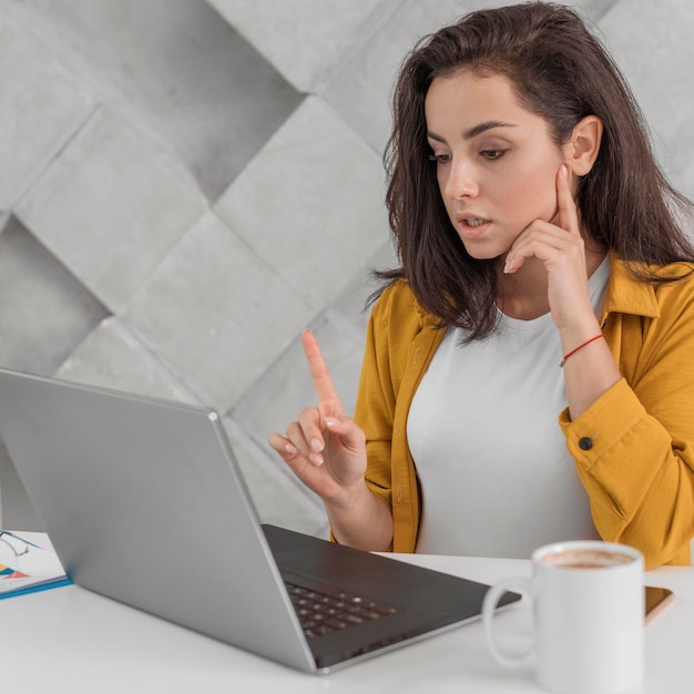 Mulher grávida mostrando um momento o dedo para o laptop em casa