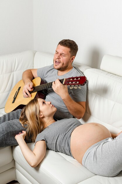 Mulher grávida, ouvindo o marido tocando violão