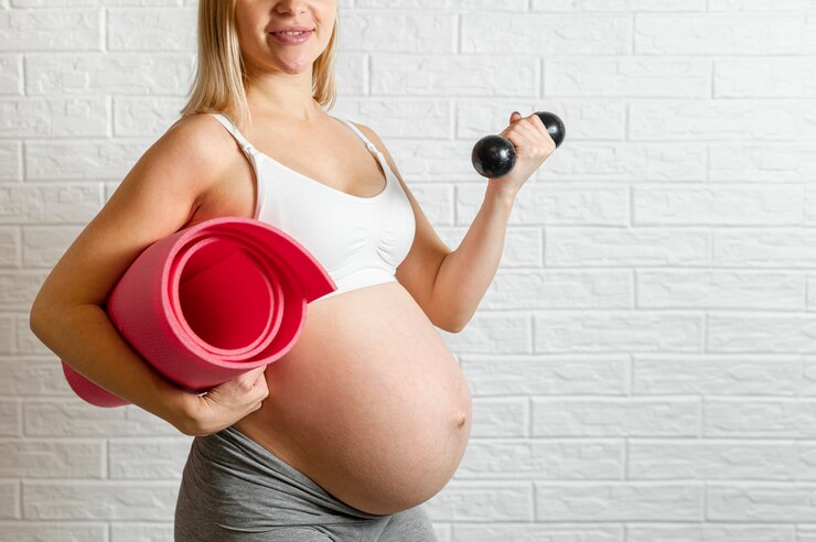 Foto grátis mulher gravida que faz o exercício da aptidão