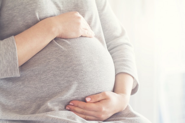 Mulher gravida que toca em sua barriga