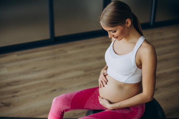 Mulher grávida se exercitando em uma aula de pilates