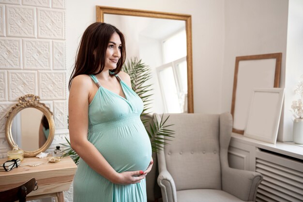 Mulher grávida segurando a barriga e olhando para longe