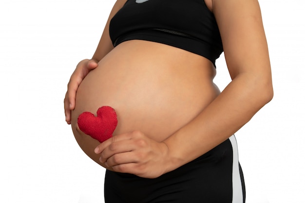 Mulher grávida segurando uma placa de coração na barriga