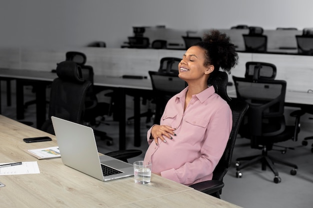 Foto grátis mulher grávida sorridente de tiro médio no trabalho