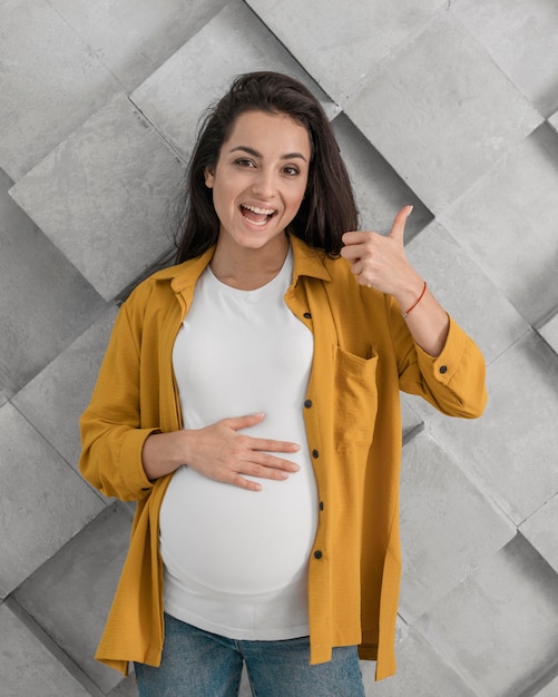 Foto grátis mulher grávida sorridente fazendo sinal de positivo