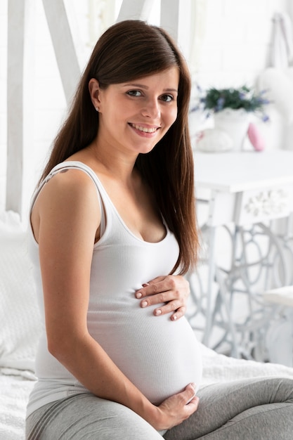 Mulher grávida sorridente, olhando para a câmera