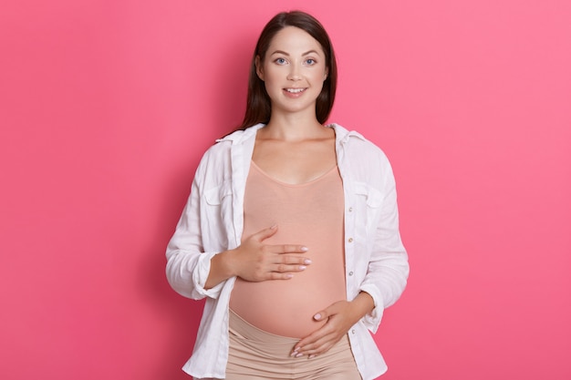 Mulher grávida vestindo roupas casuais com sorriso encantador