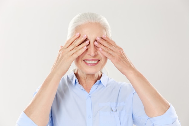 Mulher grisalho sênior, cobrindo os olhos com as duas mãos