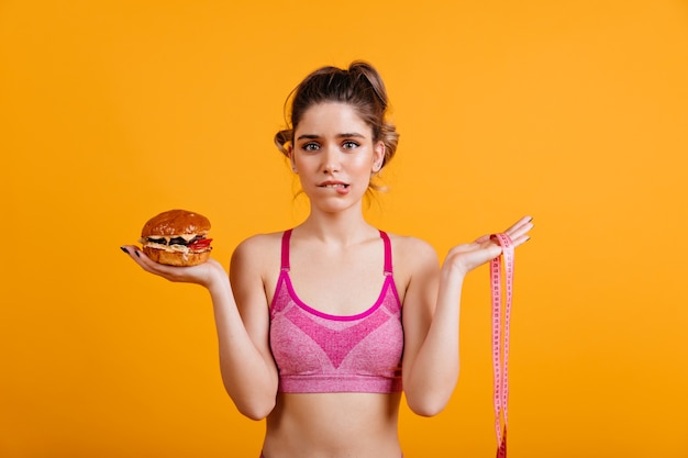 Foto grátis mulher hesitante segurando cheeseburger