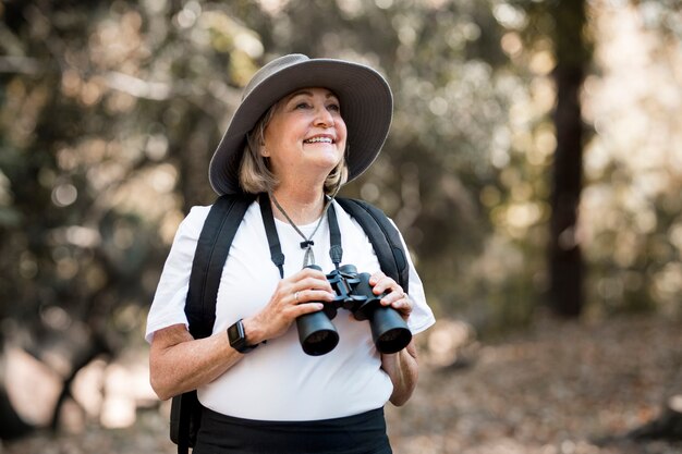 Mulher idosa ativa usando binóculos para ver a beleza da natureza