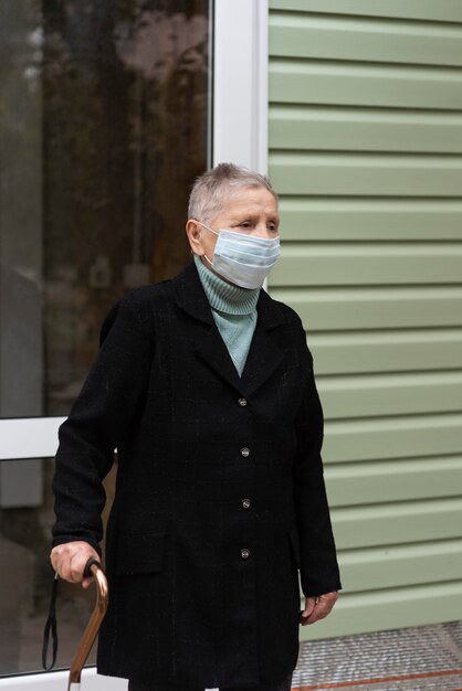 Mulher idosa com máscara médica e bengala