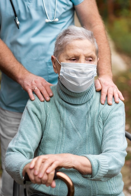Mulher idosa com máscara médica e enfermeiro em casa de repouso