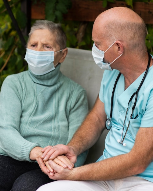 Mulher idosa com máscara médica e enfermeiro