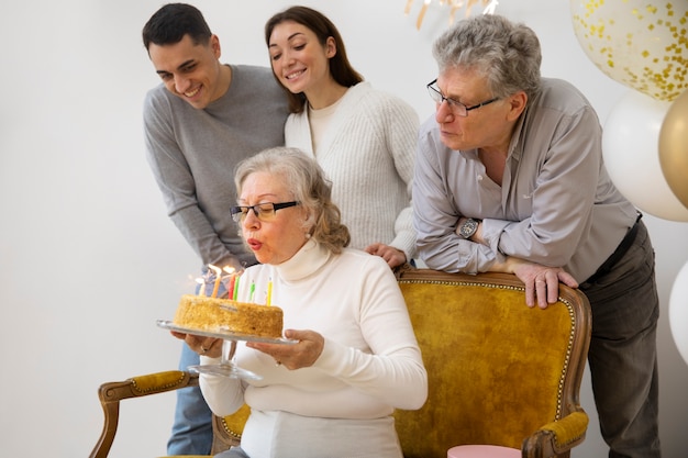 Mulher idosa com tiro médio soprando velas