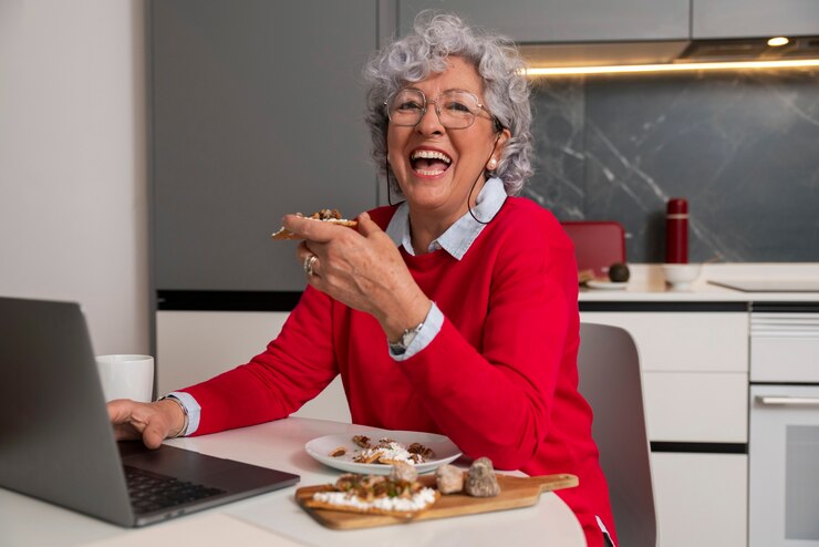 Foto grátis mulher idosa comendo prato de figos em casa e usando laptop