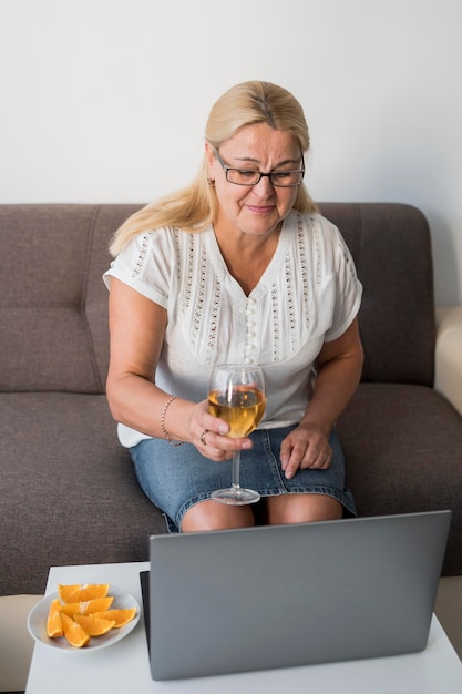 Foto grátis mulher idosa em quarentena tomando uma bebida com o laptop