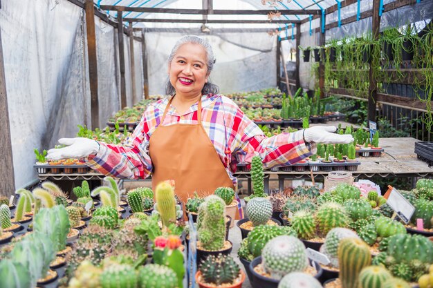 Mulher idosa feliz com uma fazenda de cactos