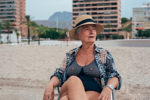 Mulher idosa na praia usando um chapéu de palha