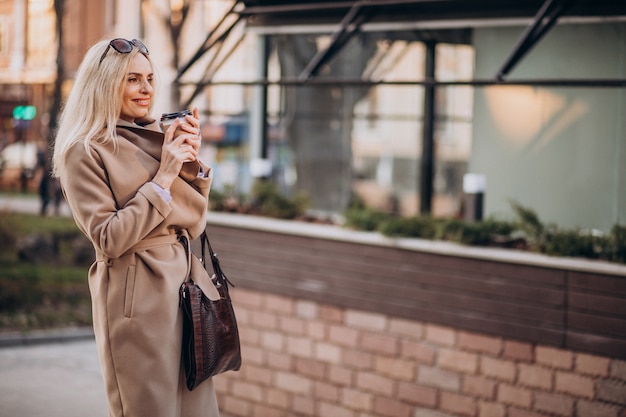 Mulher idosa tomando café fora da rua