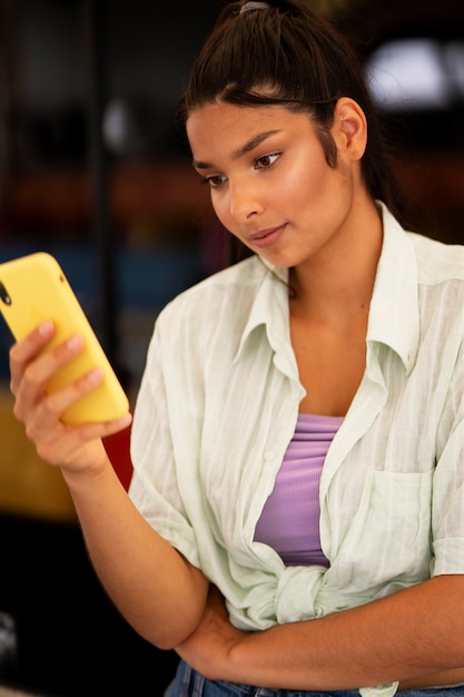 Foto grátis mulher indiana de tiro médio segurando smartphone