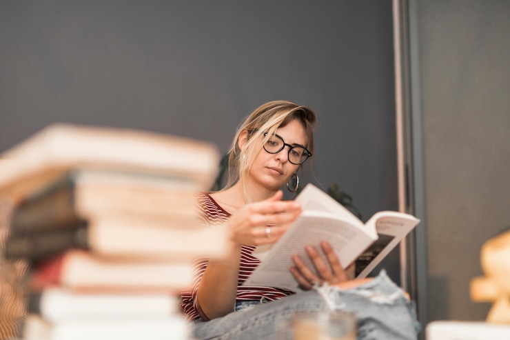 Foto grátis mulher inteligente, lendo o livro em casa