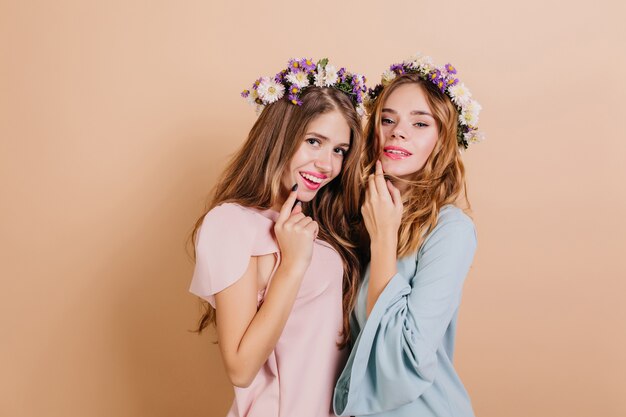 Mulher interessada com flores brancas e roxas no cabelo posando com a irmã