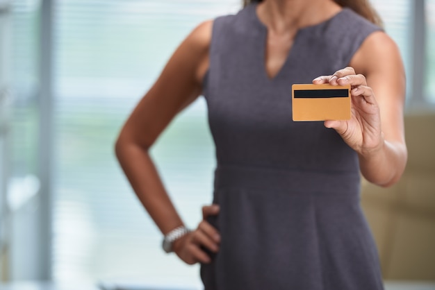 Mulher irreconhecível recortada, segurando um cartão de banco