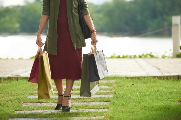 Mulher irreconhecível, vestindo roupa elegante andando com sacolas de compras