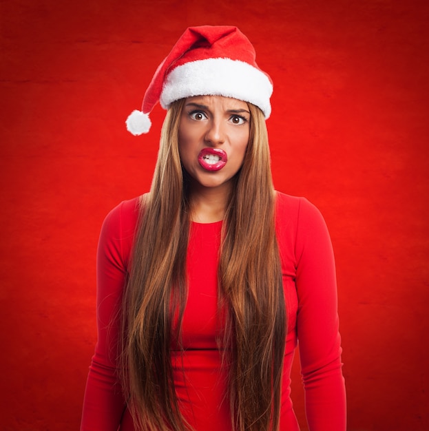 Foto grátis mulher irritada com o chapéu de santa em um fundo vermelho