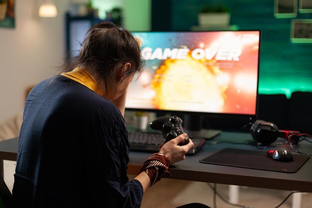 Mulher irritada jogando videogame online com joystick. Jogador usando o controlador no computador para jogar jogos de internet e perder. Pessoa decepcionada com equipamentos de jogos eletrônicos.