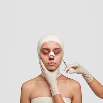 Mulher isolada com tiro vertical com hematomas e marcas de elevação, recebe injeção no rosto antes da operação de plástico