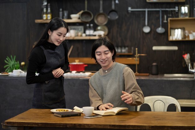 Mulher japonesa e homem lendo do notebook em um restaurante