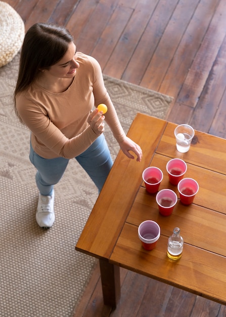 Mulher jogando cerveja pong em uma festa coberta