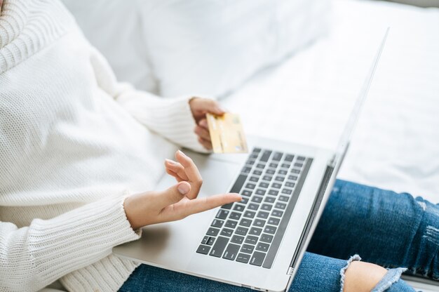 Mulher jogando laptop e segure um cartão de crédito.