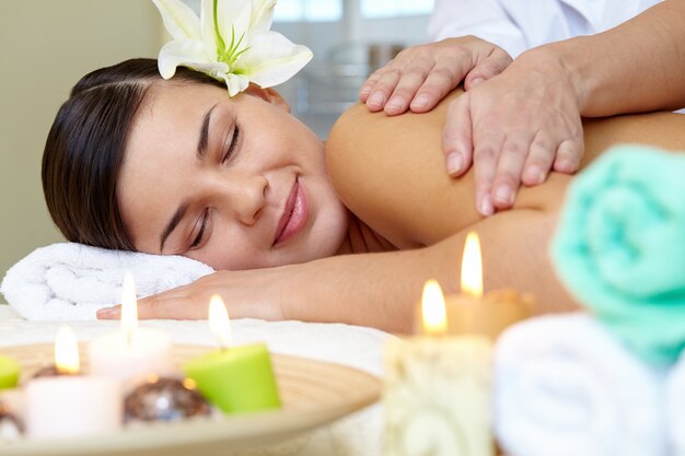 Mulher jovem a desfrutar de uma massagem nos ombros.