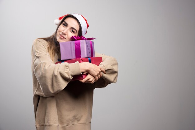 Mulher jovem abraçando dois presentes de Natal