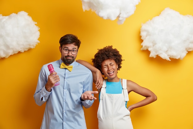 Foto grátis mulher jovem afro-americana deprimida e chorosa, com humor inconstante, inclina-se sobre o ombro do marido que olha com hesitação