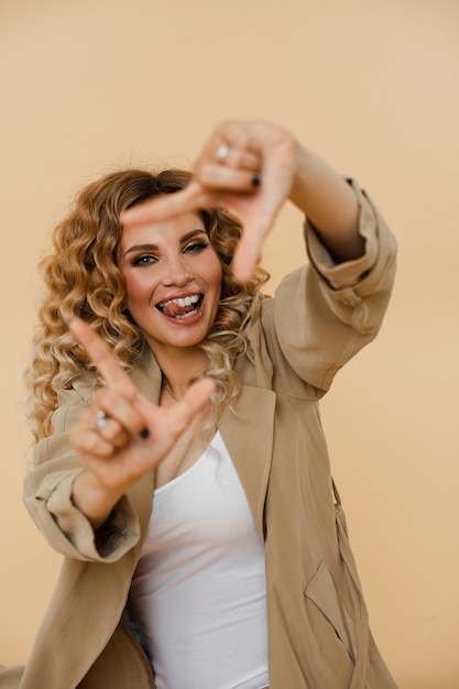 Mulher jovem alegre sorrindo e fazendo uma moldura com os dedos. Conceito de moda