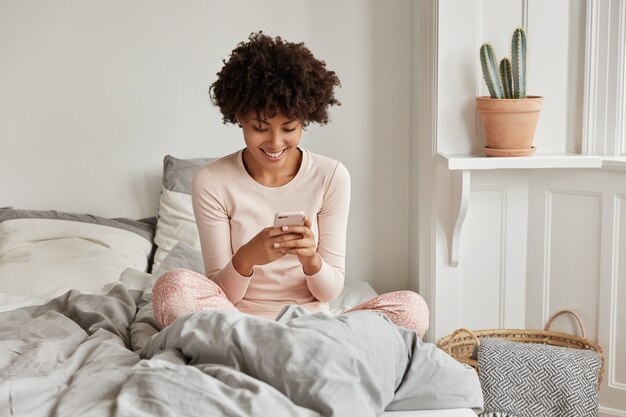 Mulher jovem animada com seu telefone posando em casa