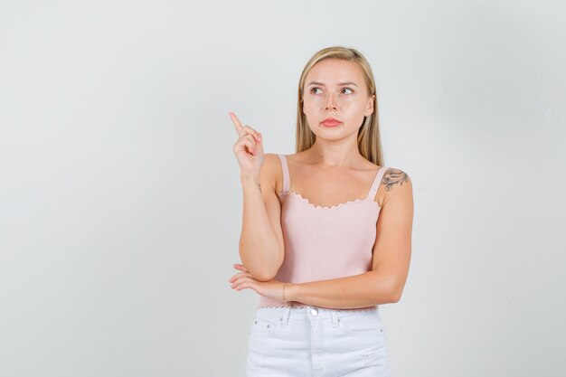 Mulher jovem apontando para o lado e olhando para o lado na camiseta