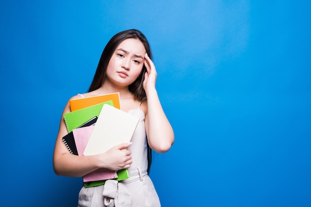 Mulher jovem asiática bonita lendo livro isolado na parede azul