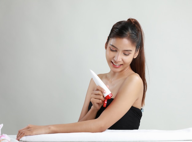 Mulher jovem asiática segurando o tubo de creme hidratante