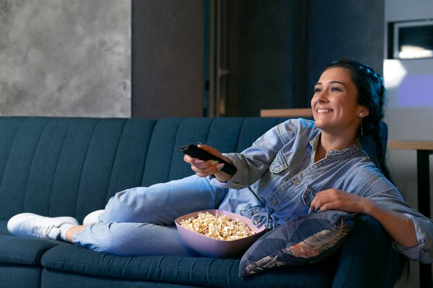 Mulher jovem assistindo serviço de streaming em casa