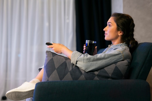 Foto grátis mulher jovem assistindo serviço de streaming em casa