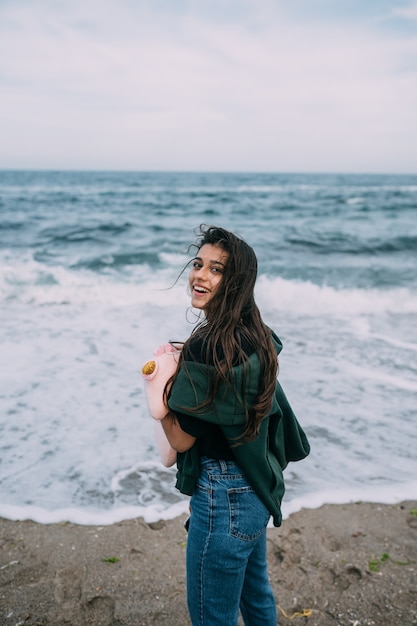 Mulher jovem atira em um smartphone as ondas do mar