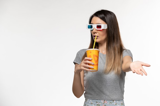 Mulher jovem bebendo refrigerante em óculos de sol D na superfície branca