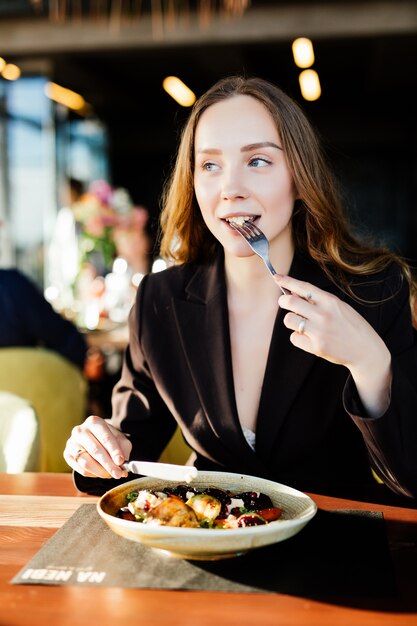 Mulher jovem bonita comendo salada em um café