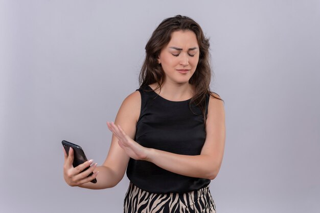 Mulher jovem caucasiana vestindo camiseta preta não quer parece um telefone na parede branca