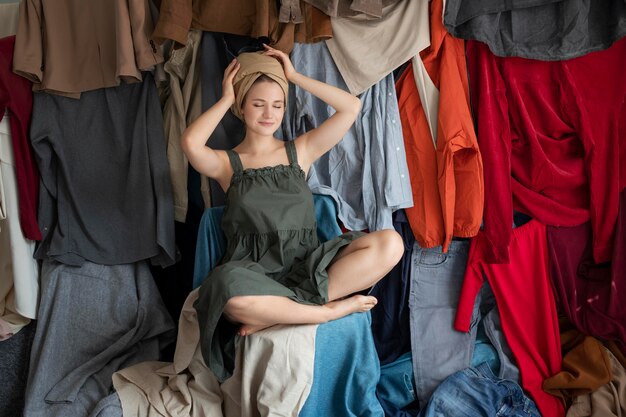 Mulher jovem cercada por pilhas de roupas